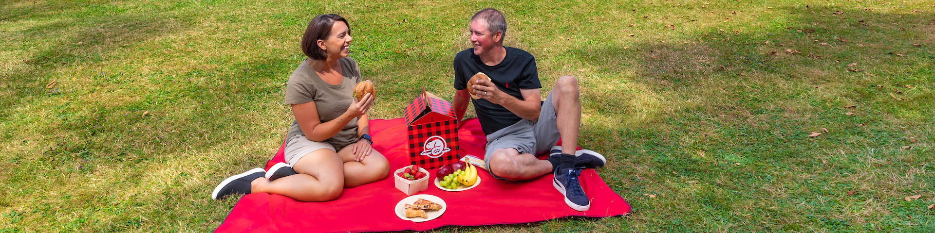A couple sitting on a blanket enjoying a picnic.