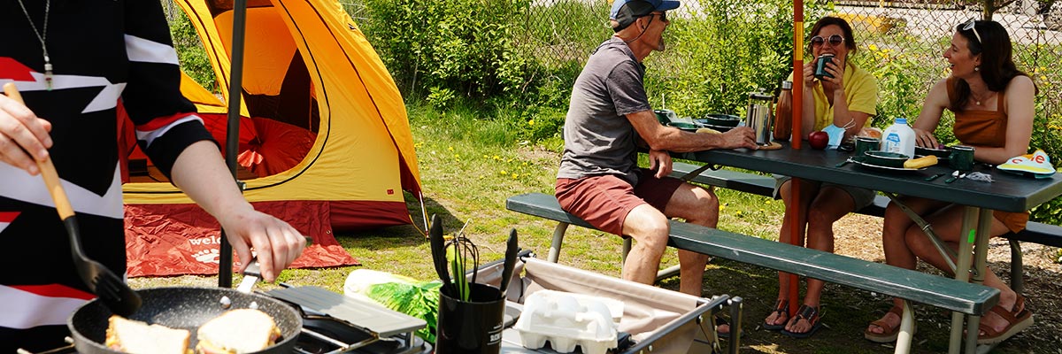 Un groupe d'amis prenant un repas en camping par une journée ensoleillée. 