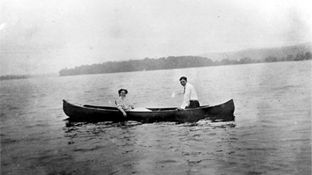 Photo en noir et blanc de deux membres de la famille Papineau en train de voguer dans un canot.