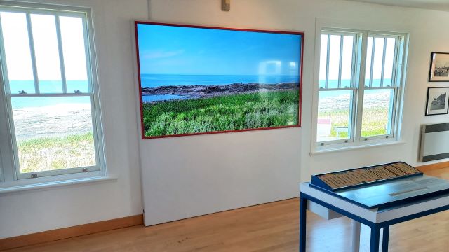Frame showing a shore scenery between two windows in an exhibit room.