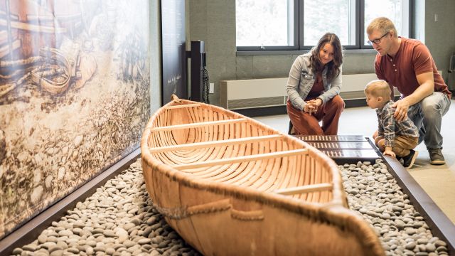 A family looks at a mi'kmaq birch canoe