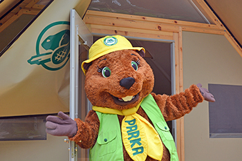 Parka, la mascotte de Parcs Canada, devant la porte d’une tente oTENTik