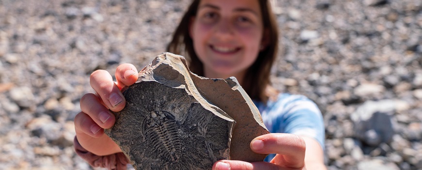 a child holding up a fossil to the camera