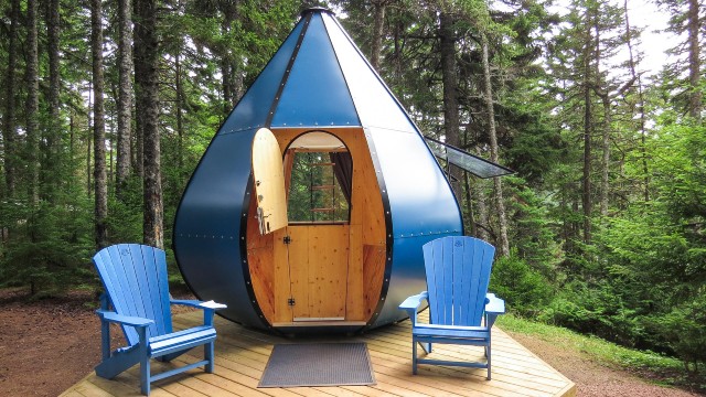 The Ôasis unit is a roofed accommodation shaped like a tear drop. Its shape and blue color create a beautiful contrast with the forest background