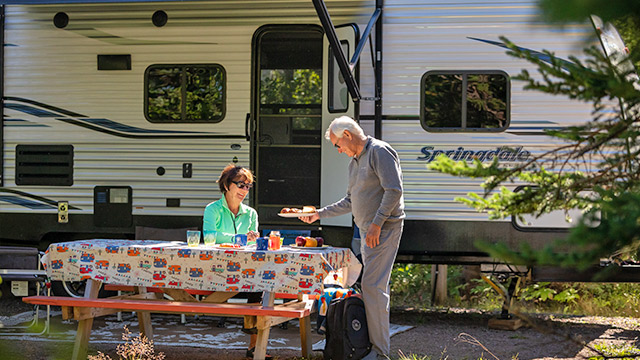 A man and woman cook lunch at their camper