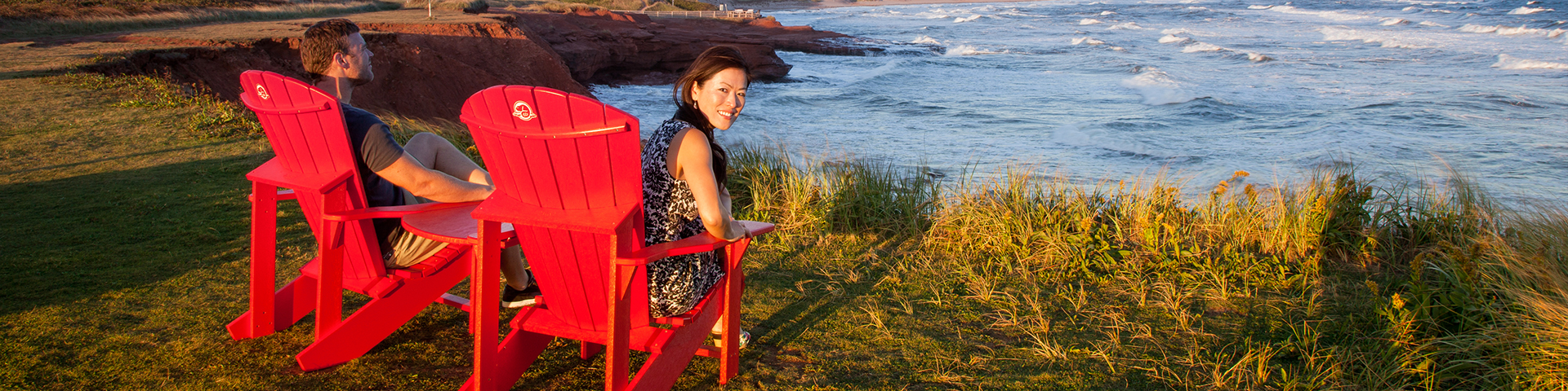 A couple enjoys the view at PEI National Park from the Red Chairs