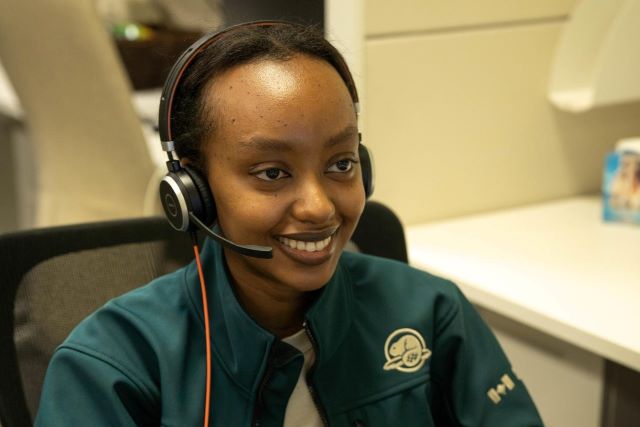 A student employee of African descent speaks into a headset.