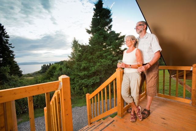 A retired couple on the porch of an oTENTIk tent looking out over the landscape. 