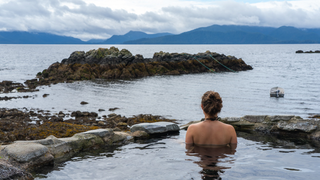 A person looks at the ocean in the hot springs on Hotspring Island in Gwaii Haanas National Park Reserve.