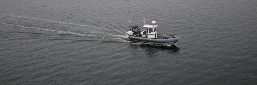 Vue d’un bateau pneumatique de Parcs Canada naviguant sur l’eau calme.