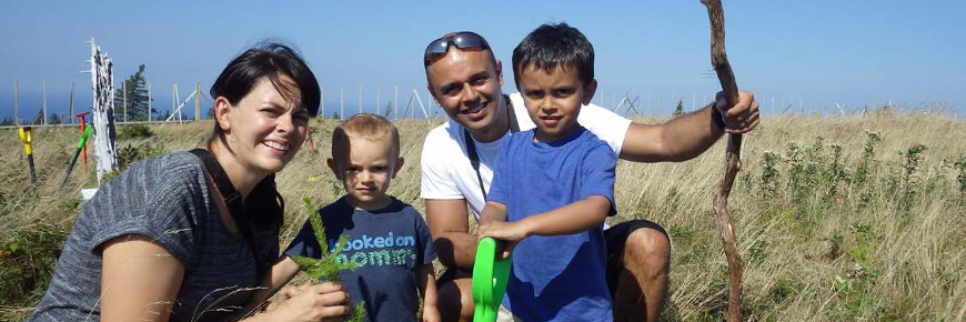 A man and woman crouching beside two small children in a field.