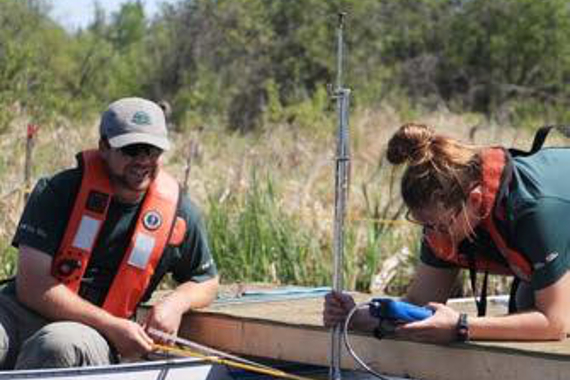 Une femme sur un quai examinant un moniteur portatif, un homme à ses côtés.