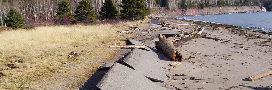Un chemin d’accès fragmenté et déformé le long d’un ravage.