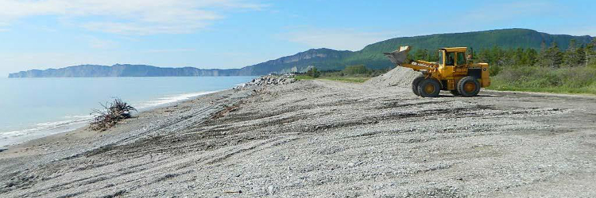 A bulldozer on a sloped gravel beach.