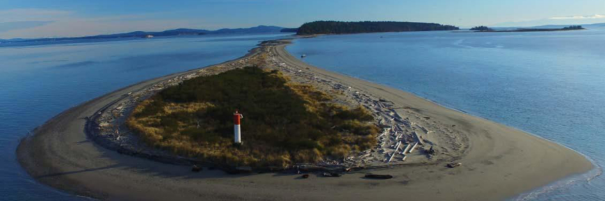 Vue aérienne d’un feu de navigation situé sur la rive d’une péninsule de sable.