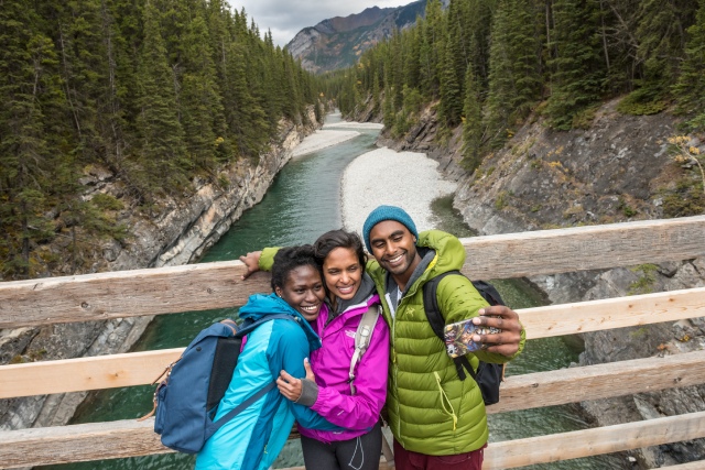 A group of millennials take a selfie while hiking on the Lake Minnewanka Trail.