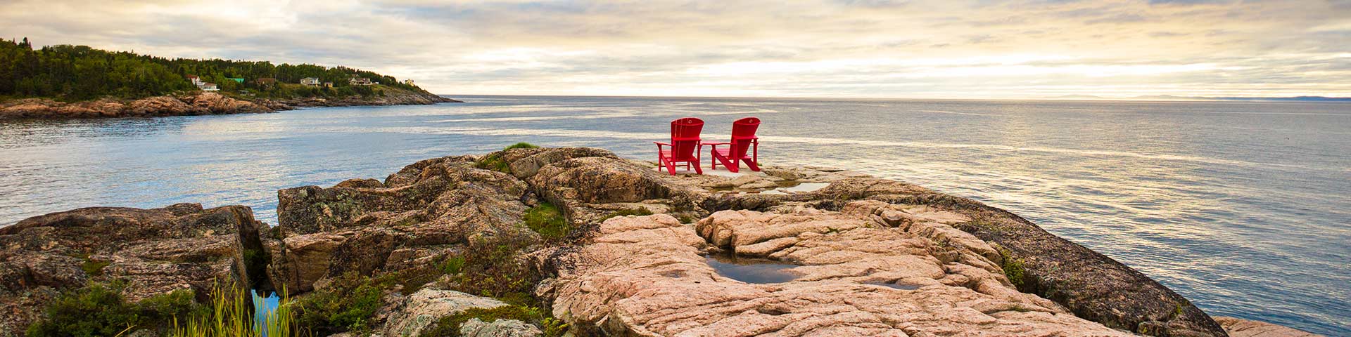 Two red chairs on an outcrop of rocks facing the ocean at Saguenay-St-Lawrence Marine Park, Quebec.