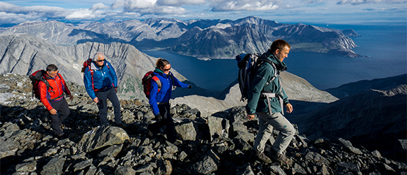 Employee accompanying three visitors on a hike, mountains in the background