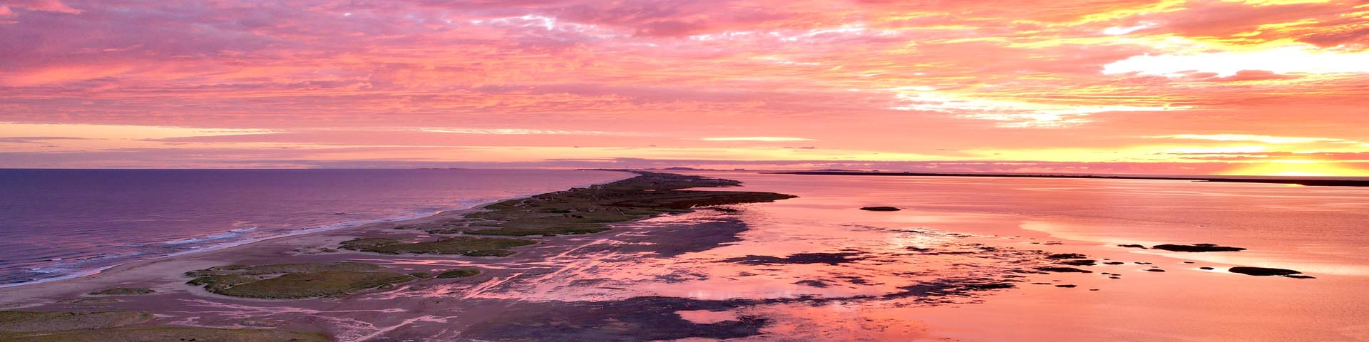 Une section du ciel, du littoral et de l'océan dans la zone proposée pour l'étude de faisabilité. Le soleil se lève dans les nuages, créant un ciel multicolore et son reflet sur l'eau.