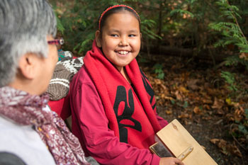 A local First Nations girl and her grandmother demonstrate traditional knitting processes at McDonald Campground. Gulf Islands National Park Reserve.