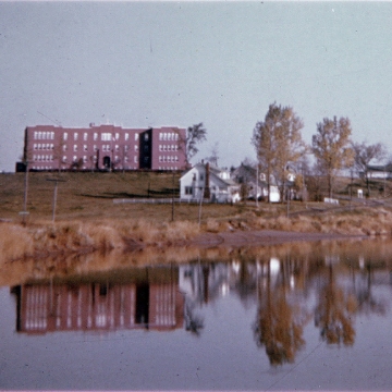 Former Shubenacadie Indian Residential School National Historic Site with trees, in front of water area