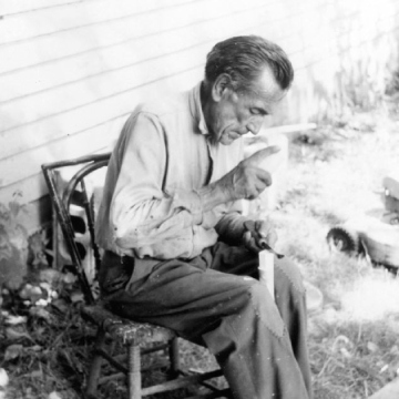 Black and white photo of a man seated on a chair