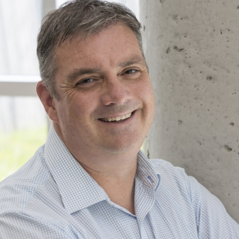 A man posing for the camera, smiling with a bright shirt