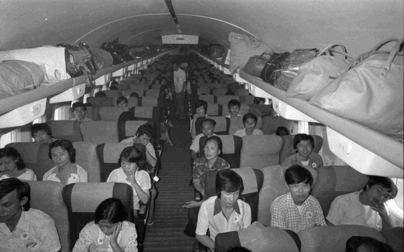 Photo en noir et blanc de l'intérieur d'un avion et des personnes assises