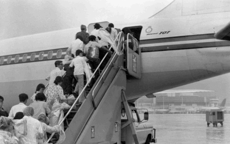 Black and white photo of people walking up steps to an airplane