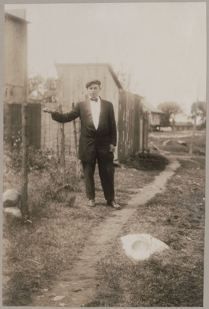 Historical photo of a man standing near a fence