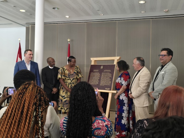 Group of people standing beside a commemorative plaque and attendance watching