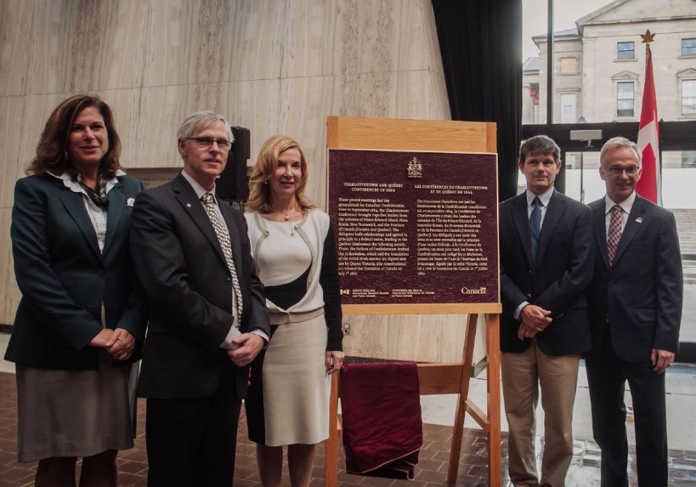 Five people standing around a commemorative plaque