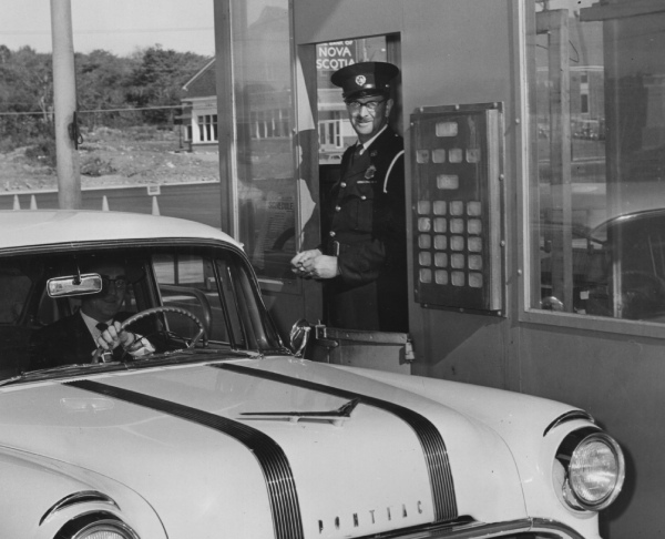 Commissionaire working and car in front of a tollbooth, Halifax, Nova Scotia, 1955