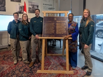 A group of people is standing near a commemorative plaque placed on an easel