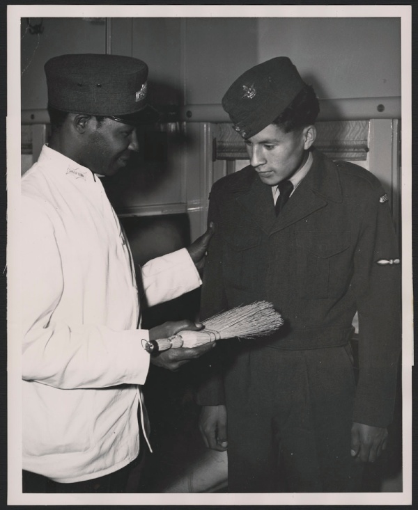 A Black railway porter dusting off a passenger, 1958