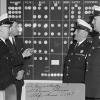 Members of the Canadian Corps of Commissionaires deliberating in front of an assignment board, Nova Scotia, 1967