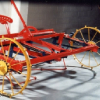 A red and yellow metallic agriculture machine on display