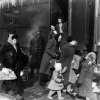 People walk alongside a train carriage with their suitcases, 1948