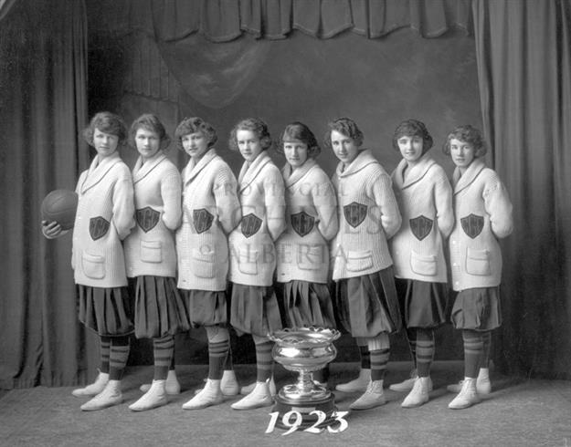 Photo en noir et blanc d'un groupe de femme avec un trophée gagnant et un ballon de basketball