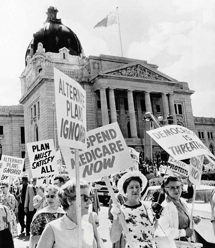 Protest marchers with signs gather in front of the Legislative Building during Protest Parade in Regina, Saskatchewan, 1962