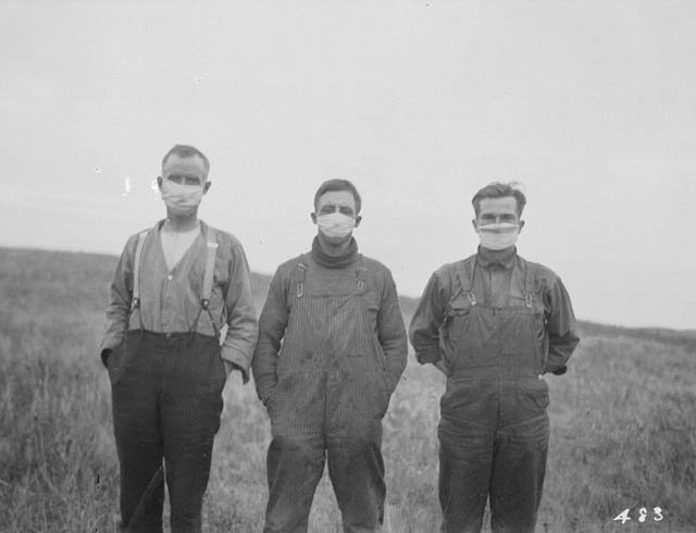 Black and white photo of three men wearing a mask