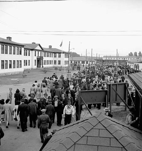 Male and female workers leaving Defence Industries Limited to board passenger train, 1944