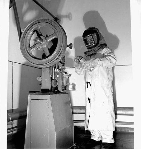 Female worker wearing an asbestos suit and head and face protection at Defence Industries Limited, 1944