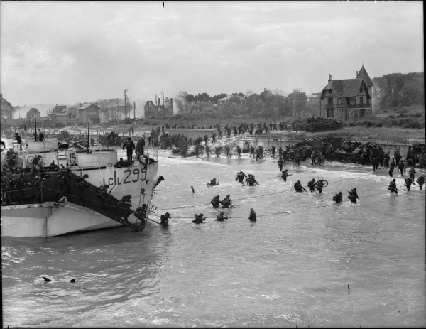 Soldiers disembark from a boat onto a beach, 1944