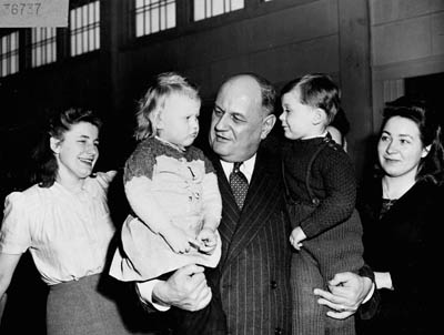 Photo historique de deux enfants dans les bras d'un homme souriant
