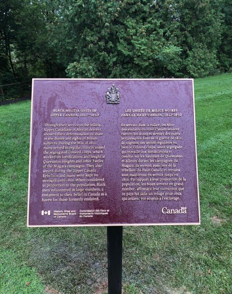 Commemorative plaque for Black Militia Units in Upper Canada, 1812-1850 National Historic Event with grass and forest surroundings