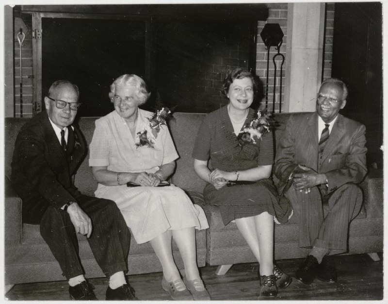 Black and white photo of four persons seated on a sofa