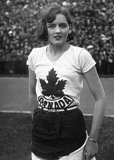 Photo en noir et blanc d'une femme debout portant un t-shirt sur lequel il y a une feuille d'érable et le mot Canada