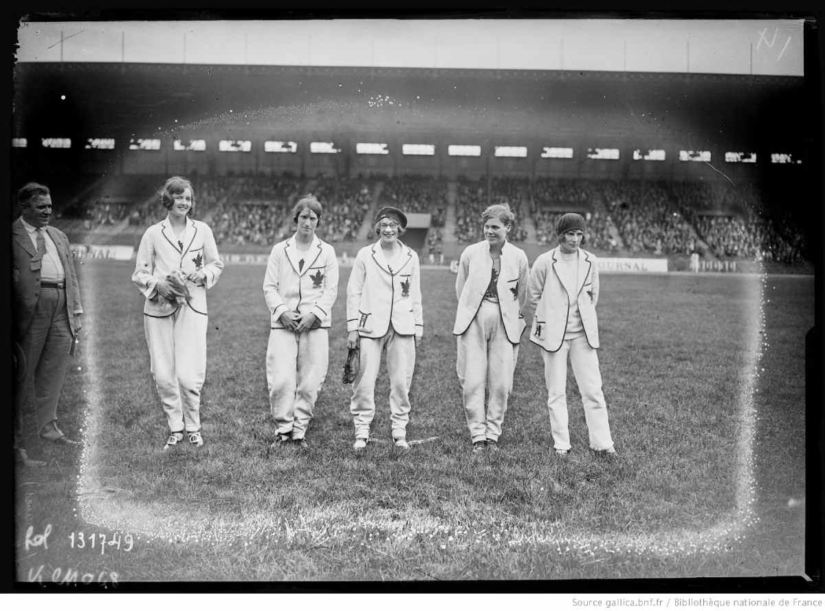 Photo en noir et blanc d'un groupe de femme et d'un homme debout au centre d'un stade