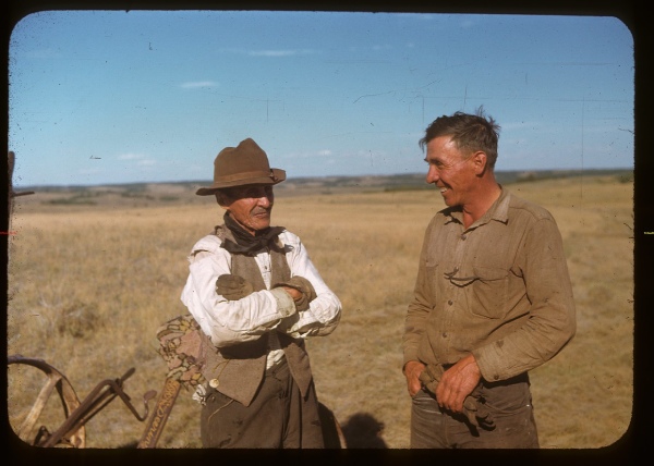Deux hommes discutent et sourient, debout dans un champ, dans les années 1950